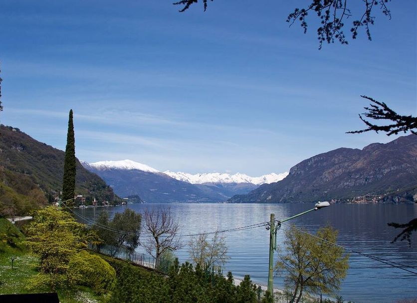 Villa Ucci in Onno overlooks a serene lake with mountains and snow-capped peaks in the distance
