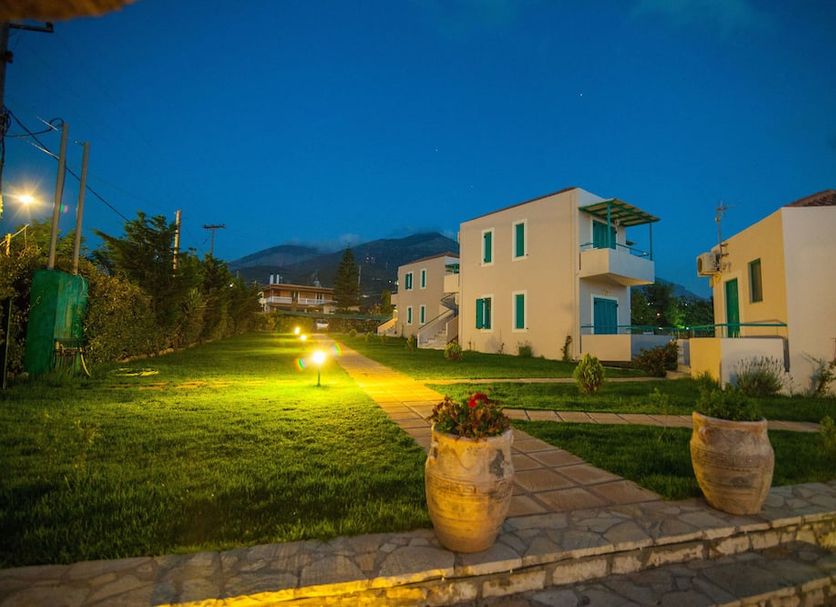 Kyparissia Blue Boutique Hotel in Kyparissía at dusk, with lawn, lit pathway, and white guest buildings