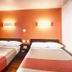 Motel 6 Mammoth Lakes room with two beds, orange wall, wall lights and red curtains