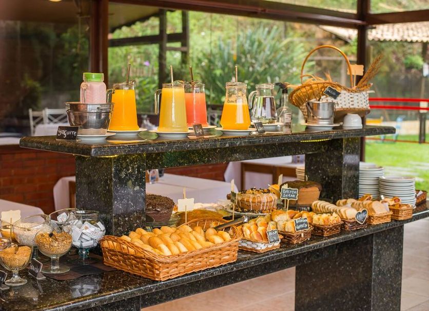 Hotel Serra Everest, Nova Friburgo: breakfast buffet with pastries, bread, fruit, and juice on a counter