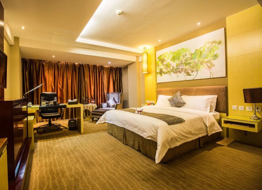 Changchun Huatian Hotel in Changchun guest room with king bed, desk, sofa and warm lighting