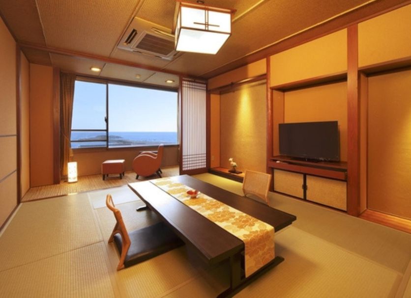 Houraiya in Kamogawa tatami room with low table, TV, and ocean view through window