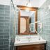 Casa Chitic in Brașov bathroom with wood-framed mirror, sink, glass shower and green tile walls