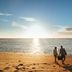 Guests walk on a sandy beach at Mackerel Islands, Onslow, with ocean sunset views