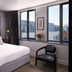 Titanic Hotel Belfast guest room with king bed, black chair and large windows overlooking Belfast