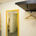 Bo - Álvares Cabral Guesthouse in Porto: yellow-framed mirror, wall hooks, and hanging clothes rack
