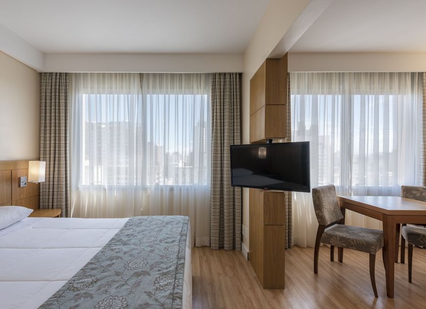 Monreale Plus São José dos Campos guest room with two beds, desk, TV and city-view windows