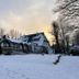 Hotel Waldesruh Am See in Aumühle, snow-covered lakeside hotel with trees at sunset