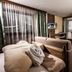 Pension Kreuzjoch, Zell am Ziller: cozy room with sofa, bed and desk by large curtained windows
