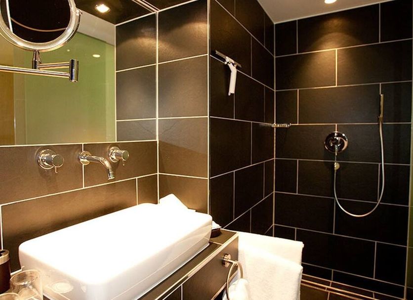 Das Posch Hotel Oberammergau bathroom with black tile shower and sink vanity