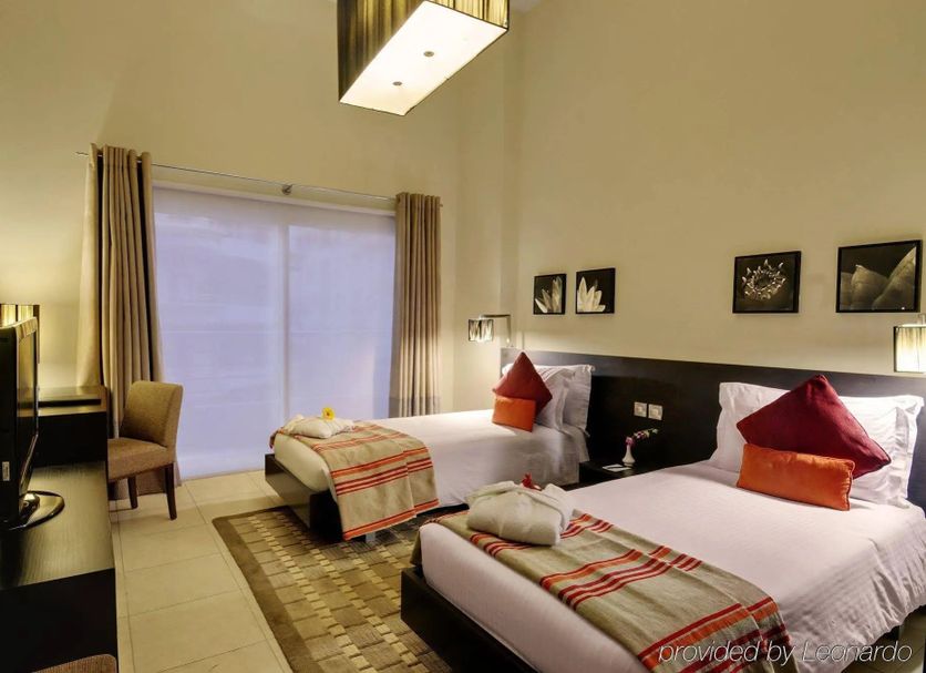 Raf Hotel Apartment in Dubai, two twin beds in a modern guest room with balcony doors and TV