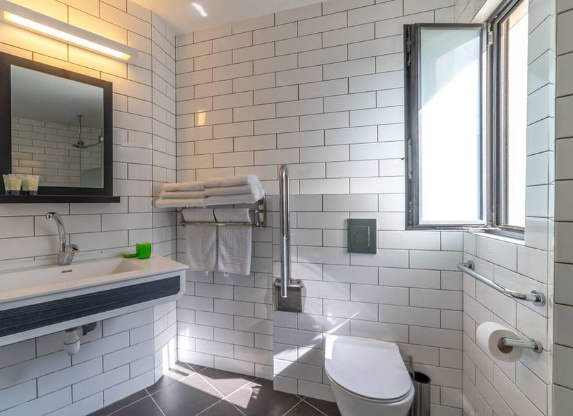 130 Rock Apartments Tel Aviv bathroom with white tile walls, vanity sink, toilet and open window