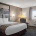 Super 8 by Wyndham Lewistown guest room with king bed, recliner, desk chair, and window view