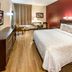 Red Roof Plus Long Island - Garden City room in Westbury with king bed, TV, and seating area