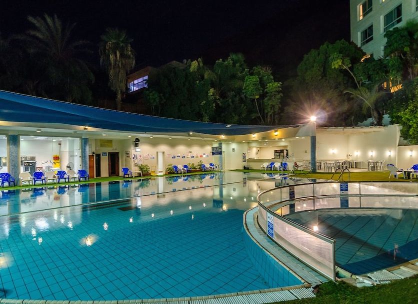 Royal Plaza Hotel in Tiberias, outdoor illuminated pool at night with lounge chairs and curved railing