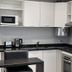 CH Recoleta Suites Buenos Aires kitchenette with stove, microwave, sink, kettle and black countertops
