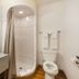 Motel 6 Dayton bathroom with shower stall, toilet, sink, and beige curtain