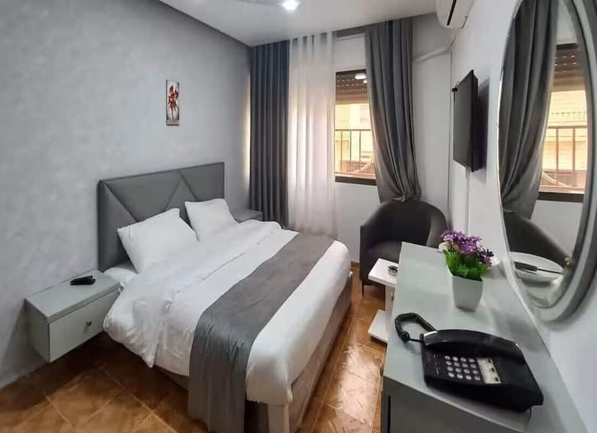 Al-Nujoom Hotel Suites, Amman: compact guest room with double bed, wall-mounted TV, window, and desk