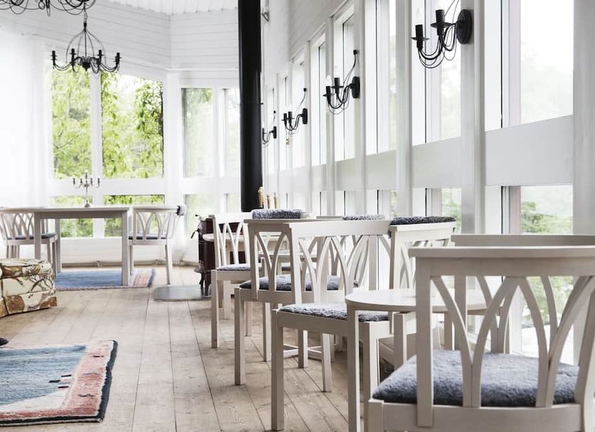 Skeviks Gård in Gustavsberg, bright dining room with white chairs and large windows
