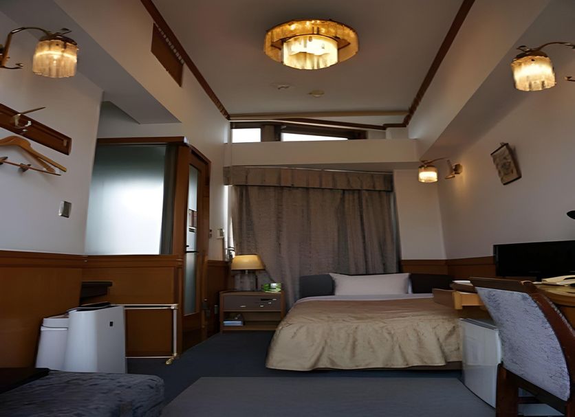 Business Hotel Crescent Tokyo guest room with bed, desk, TV, and curtained window