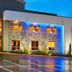 Four Points by Sheraton Little Rock Midtown exterior at night with blue-lit stone facade and wet driveway