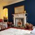 Glenan Lodge Self Catering in Inverness living room with fireplace, armchairs, plaid throws and map wall art