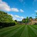 The Alfriston in Polegate, set beside a wide striped lawn and landscaped gardens under blue sky