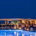 Abaton Island Resort & Spa in Hersonissos with a lit poolside lounge and palm trees at dusk