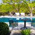 Wimberley Inn in Wimberley: poolside table and chairs beside an outdoor pool under trees