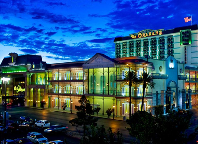 The Orleans Hotel & Casino in Las Vegas exterior at dusk with lit facade and parking lot