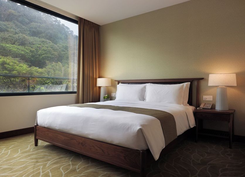 Yusense Hotel Taipei City room with king bed, bedside lamps and large window views of greenery