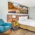 Days Inn & Suites by Wyndham Rocky Mount Golden East guest room with king bed, chair, and bathroom vanity