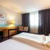 enjoyHotel garni Korntal Stuttgart room with twin beds, desk, seating area and window curtains