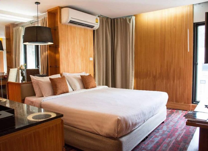 Tango Vibrant Living Hotel Bangkok guest room with king bed, wood-paneled walls and city view