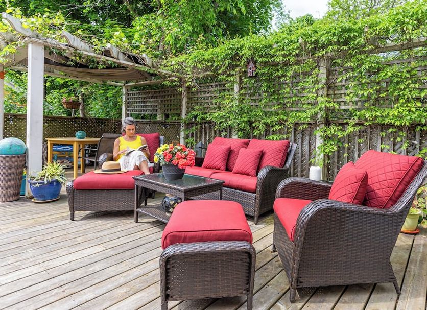 The Stella Rose B&b in Wolfville: outdoor deck with red cushioned wicker seating and lush greenery