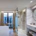 niche hotel Athens guest room with bed, marble bathroom, and balcony view over Athens