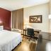 Red Roof Plus Long Island - Garden City guest room with king bed, desk, chair and window in Westbury