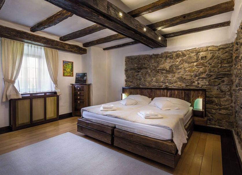 Castle Hotel Daniel room in Baraolt with exposed beams, stone wall, and a wooden bed