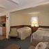 Village Green Motel South Yarmouth room with two beds, chair, lamp, and kitchenette