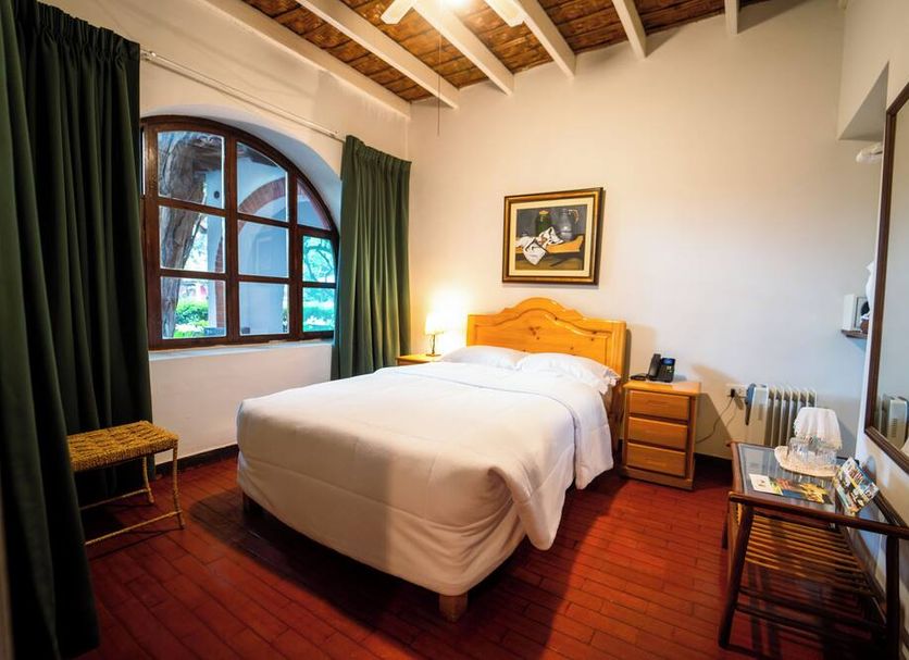 Hotel Majoro in Nazca guest room with wooden bed, arched window, and brick floor