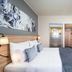 Leonardo Hotel Vienna Hauptbahnhof guest room with bed, desk, wall-mounted TV and wood accents in Vienna