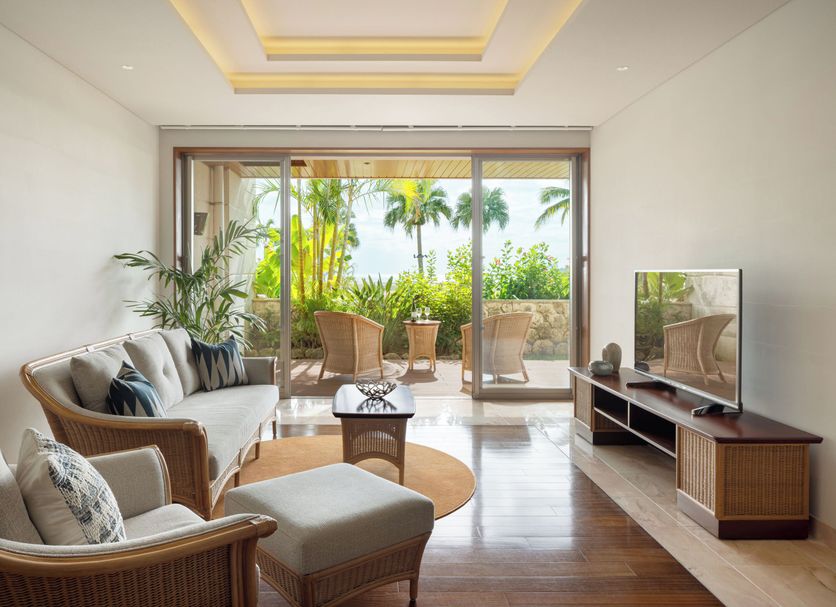 The Ubufuru Ishigaki living room with balcony, wicker seating, and tropical palm view in Ishigaki