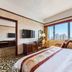 Zhiyuanlou Hotel Qingdao room with bed, desk, TV and large window with city and sea view