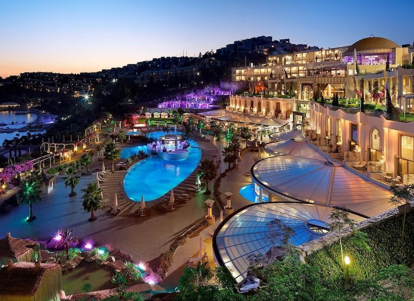Sianji Well-Being Resort in Bodrum with illuminated pools and sea views at dusk