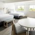 Hampton by Hilton Grand Cayman Seven Mile Beach guest room with two beds, round table and bright windows in George Town
