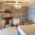 Abeliona Retreat in Ambeliona guest room with stone fireplace, exposed beams, and bed by window