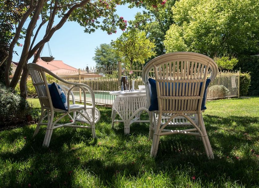 Loloma House, Armidale: shaded garden seating with wicker chairs and a small table on the lawn