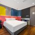 Yiting Huicheng Hotel Xiamen room with colorful accent wall, queen bed, desk and wood flooring in Xiamen