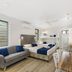 Beach House Motel Townsville room with sofa, beds, kitchenette and wall-mounted TV