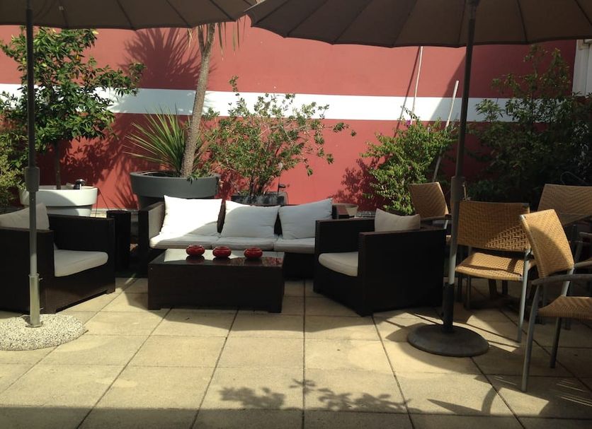 Hotel Cote Patio Nimes outdoor patio seating with umbrellas, sofa, chairs and potted plants